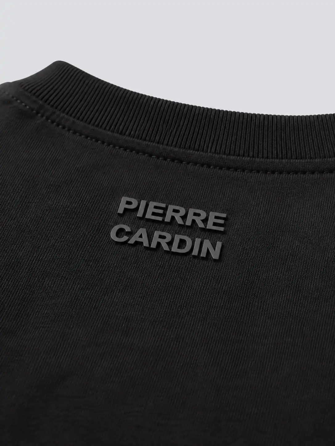 Raised high-density lettering print below the back neckline of a black long sleeve T-shirt