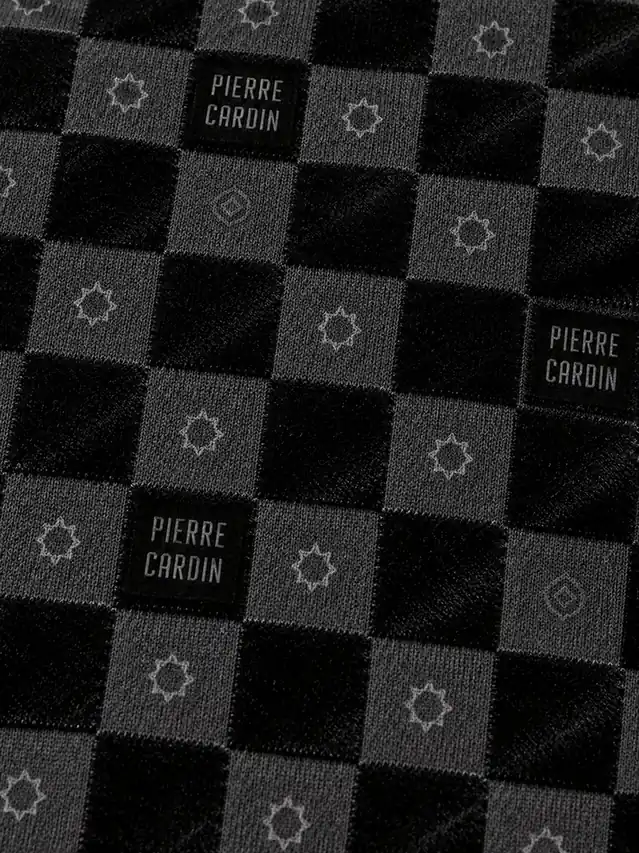 Close-up of raised light-catching black flock squares alternating with matte knit areas in a checkered polo pattern
