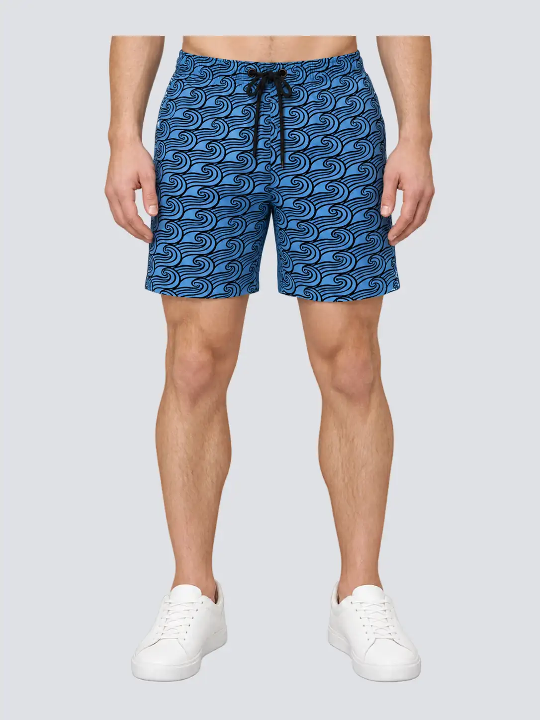 Front product visualization of blue-and-black wave print athleisure shorts on male model, with relaxed above-knee legs and drawcord waist