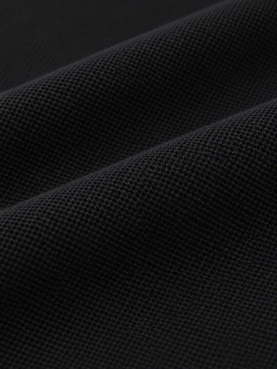 Close-up of fine black cotton pique fabric texture and soft folds