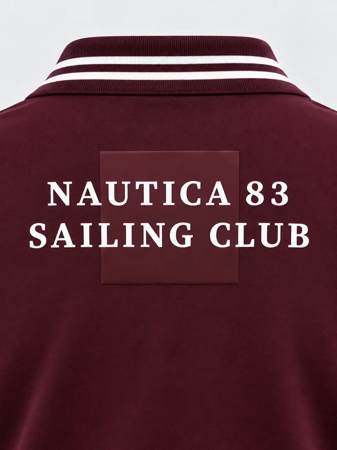 Detail of tonal burgundy rectangular silicone printing applied directly to the back of a polo shirt with white lettering across the design